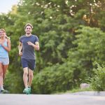 Two people jogging next to the water.